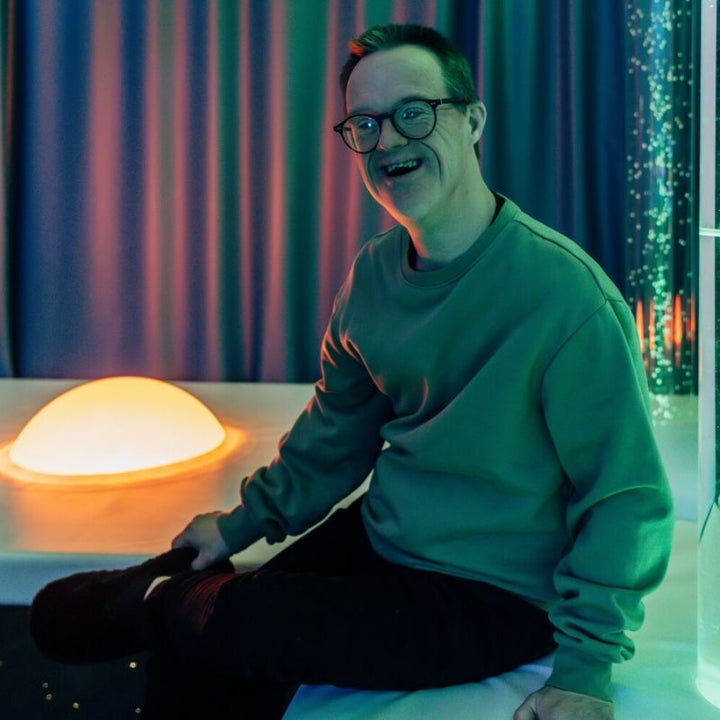 TFH Interactive Dome Swirl Podium - Happy adult sitting next to the dome 