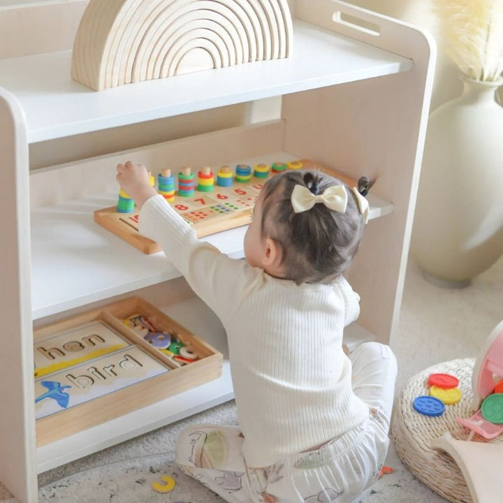 Child actively playing with materials from the Sapiens Child Banana Montessori Shelf with Borders, demonstrating the sense of order and independence the child-sized open shelf supports