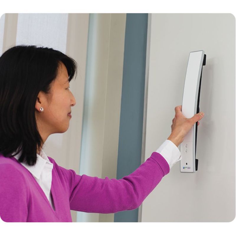 Woman attaching the Boxlight MimioTeach portable interactive whiteboard bar to a dry erase board, demonstrating the magnetic mounting setup that takes under a minute to install