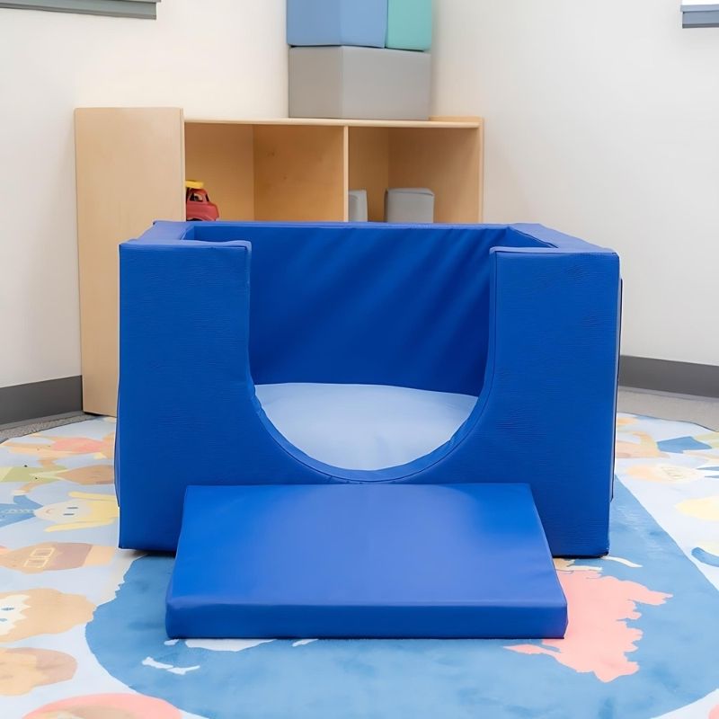 Children's Factory Cozy Cube shown indoors in a classroom or nursery setting, demonstrating the soft foam crawl-in play enclosure for infants and toddlers from 8 months