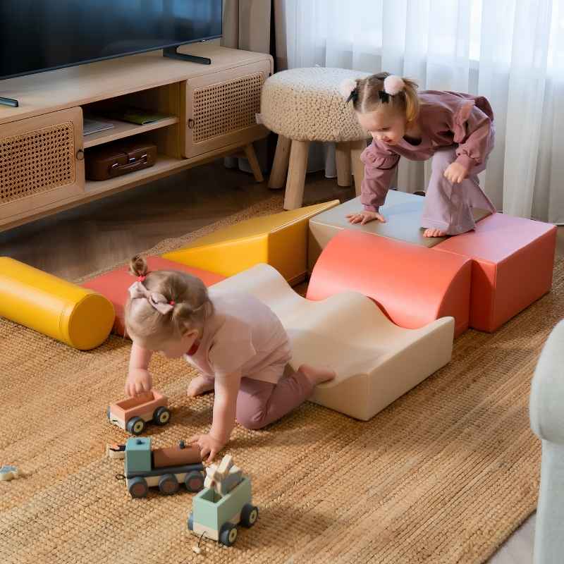 Two toddlers playing with toys beside the IGLU Discoverer Soft Play Set in Pastel Fries, a modular foam activity set