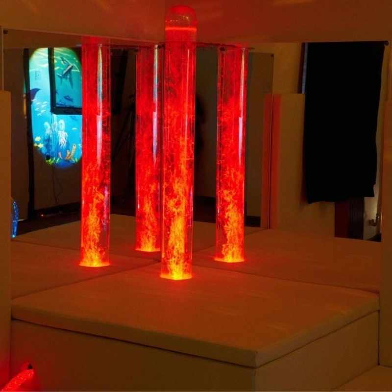 Experia Bubble Tube Mirrors corner installation glowing in red light, showing the full reflective effect of the acrylic sensory room mirror pair