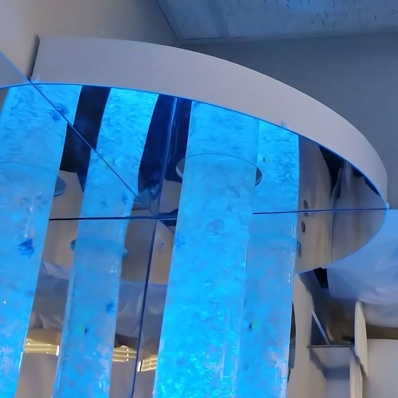 Close-up of the Experia Heavy Duty Bubble Tube Bracket showing the bolt-to-wall mounting hardware, clamping mechanism, and mirrored base for securing 6-inch diameter sensory bubble tubes in unsupervised commercial settings