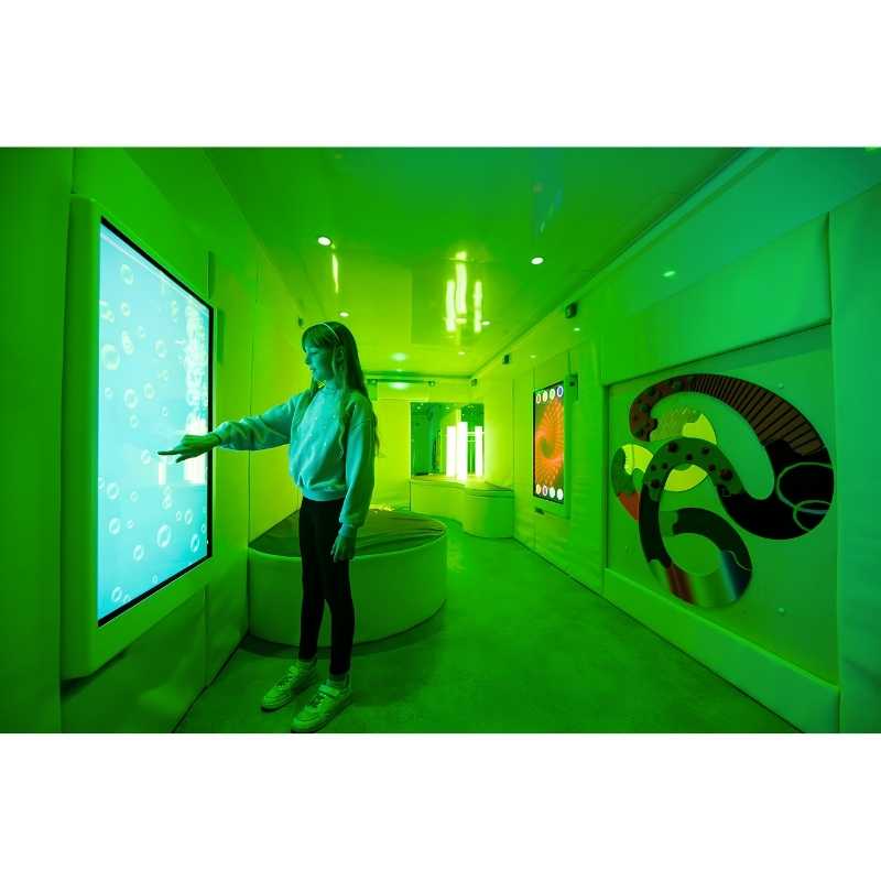 Teen engaging with the Experia Intelli Panel Bubble Wall interactive sensory panel in a green-lit therapy room