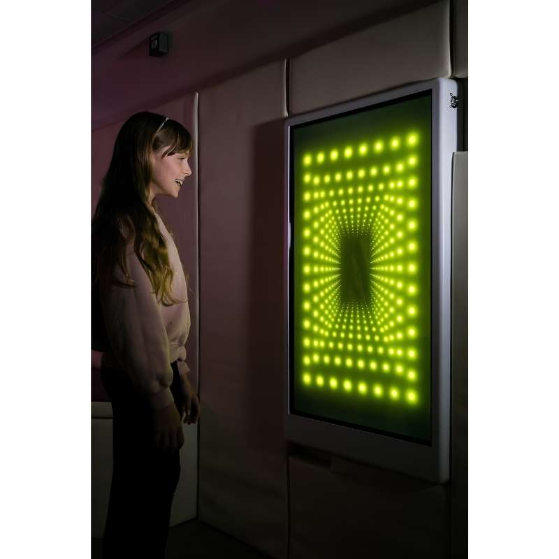 Teen engaging with the Experia Intelli Panel Infinity touchscreen sensory panel in apple green light in a darkened room