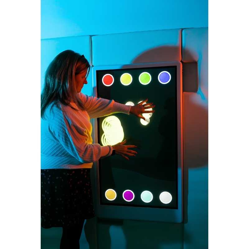 Adult engaging with the Experia Intelli Panel Musical Touch interactive sensory wall panel in multicolour light mode