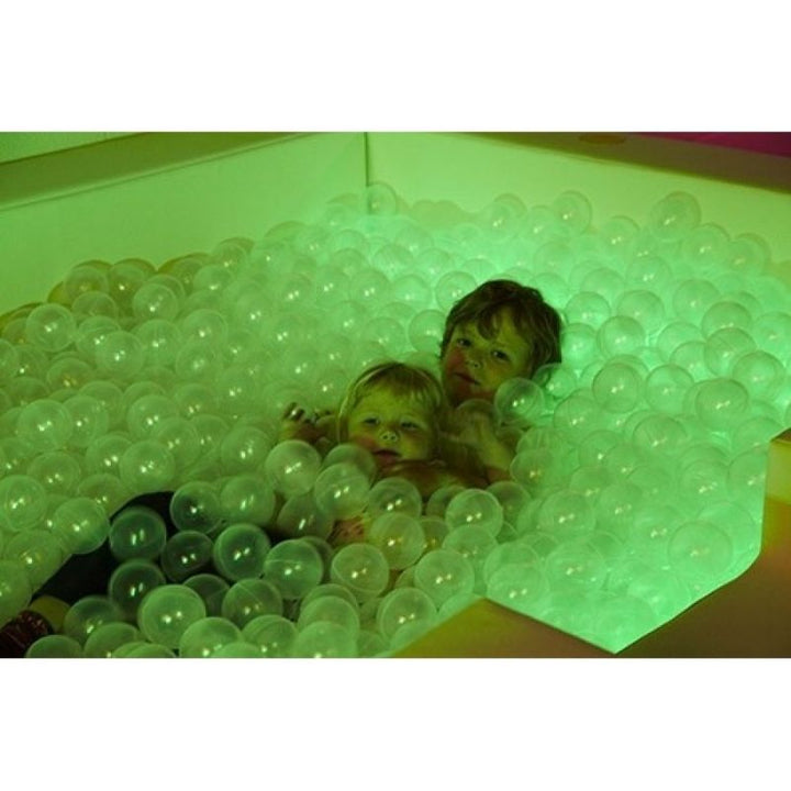 Two children playing in the Experia Interactive LED Ball Pool, demonstrating full-body tactile and vestibular sensory input from the colour-changing translucent ball pool