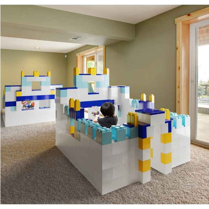 A child playing inside a walk-in fort built from the EverBlock Large Starter Kit, showing giant modular building blocks used for gross motor play at home