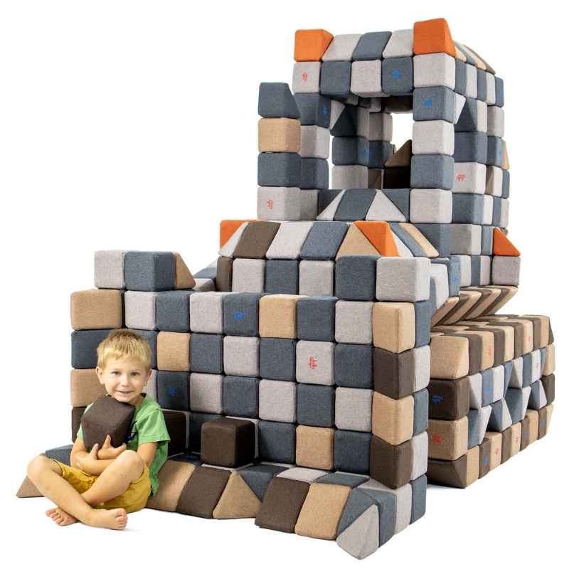 Child sitting beside a large castle structure built from JollyHeap giant magnetic building blocks in the Crazy Set