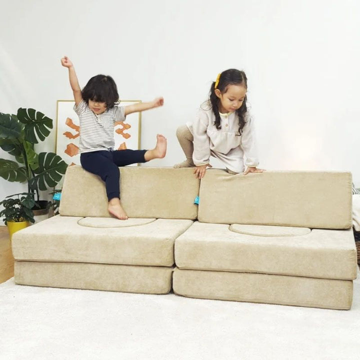 Two children in a third active play configuration with the Go Coconut Builder Bundle demonstrating the gross motor development, creative building, and enclosed sensory play value of the 7-piece Canadian-made modular foam play couch