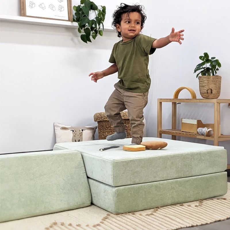 Child actively balancing and playing on Go Coconut - The Coconut modular foam play couch, demonstrating the proprioceptive input and gross motor development benefits of the CertiPUR certified foam construction