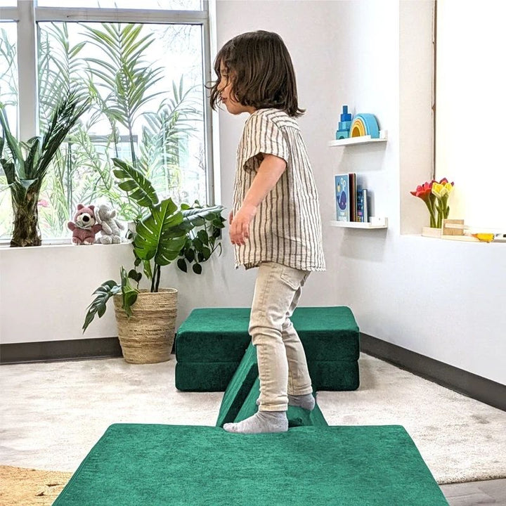 Child actively playing on Go Coconut - The Coconut in Forest Fern demonstrating the proprioceptive input, creative building, and sensory play value of the modular Canadian-made CertiPUR play couch