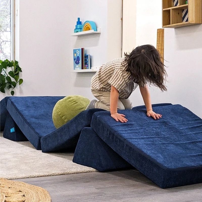Child actively playing on Go Coconut - The Coconut in Midnight Tide showing the proprioceptive input and creative modular configuration possibilities of the 100% Canadian-made CertiPUR play couch