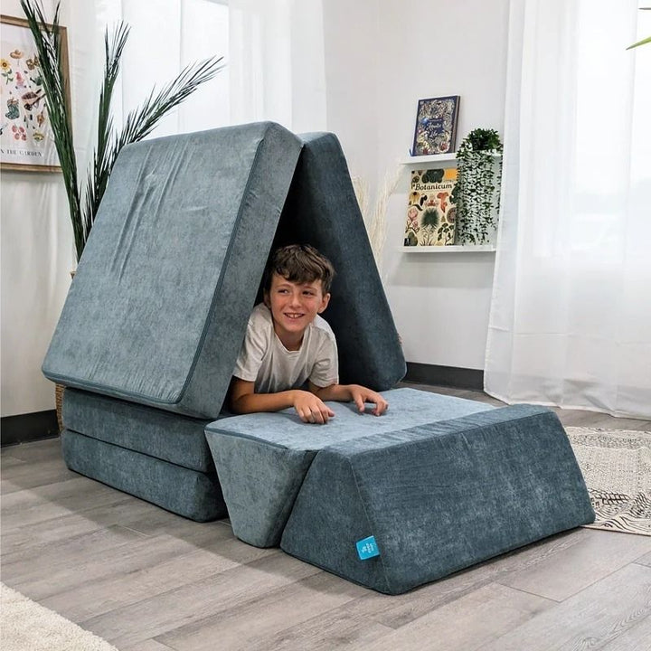 Child actively playing on Go Coconut - The Coconut in River Stone demonstrating the proprioceptive input, creative building, and sensory play value of the CertiPUR-US certified Canadian foam play couch