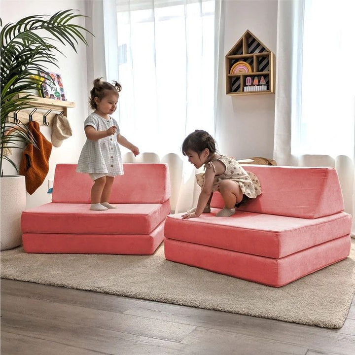 Two children actively playing on Go Coconut - The Coconut in Coral Crush demonstrating the shared creative play and open-ended Montessori-inspired foam configurations of the Canadian-made play couch