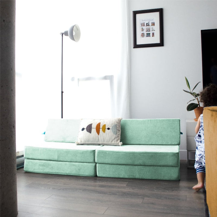 Child actively playing on the Go Coconut Half Coconut modular foam couch, demonstrating climbing and vestibular sensory development