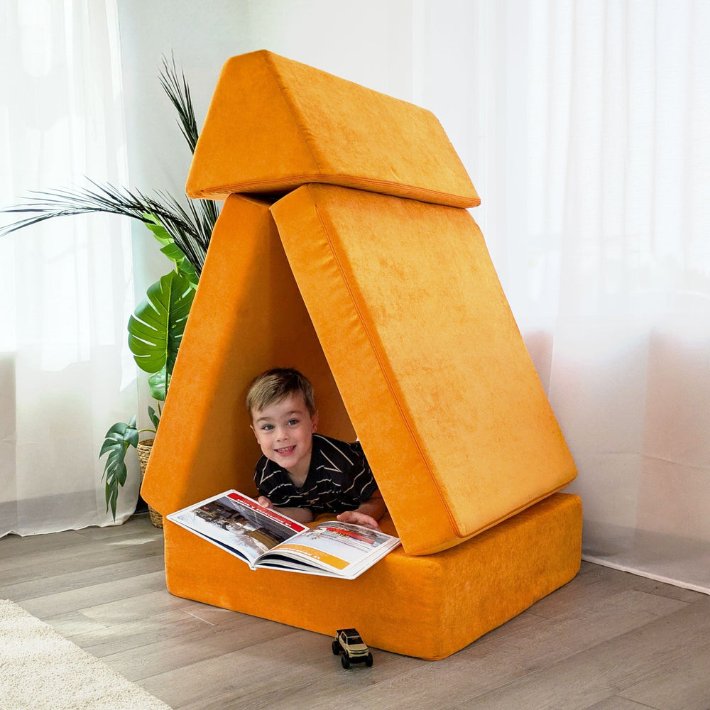 Child inside a fort built from the Go Coconut Half-Coconut Maxi Bundle modular play couch pieces in orange, demonstrating imaginative indoor play and creative builds