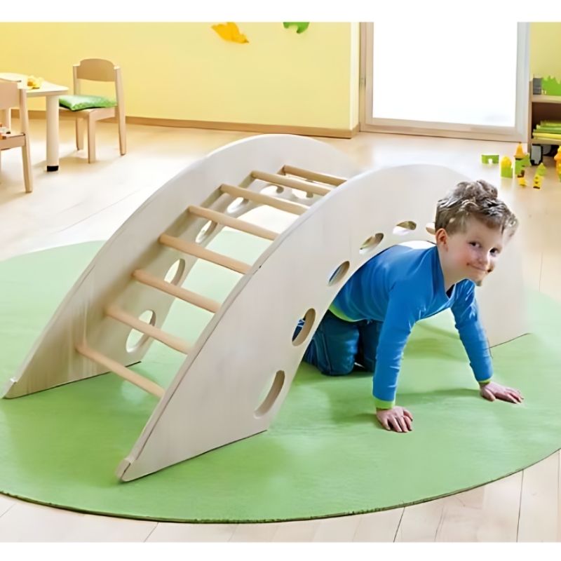 Child crawling under the HABA Pro Climbing Arch, demonstrating the multi-function design that supports crawl-through gross motor play