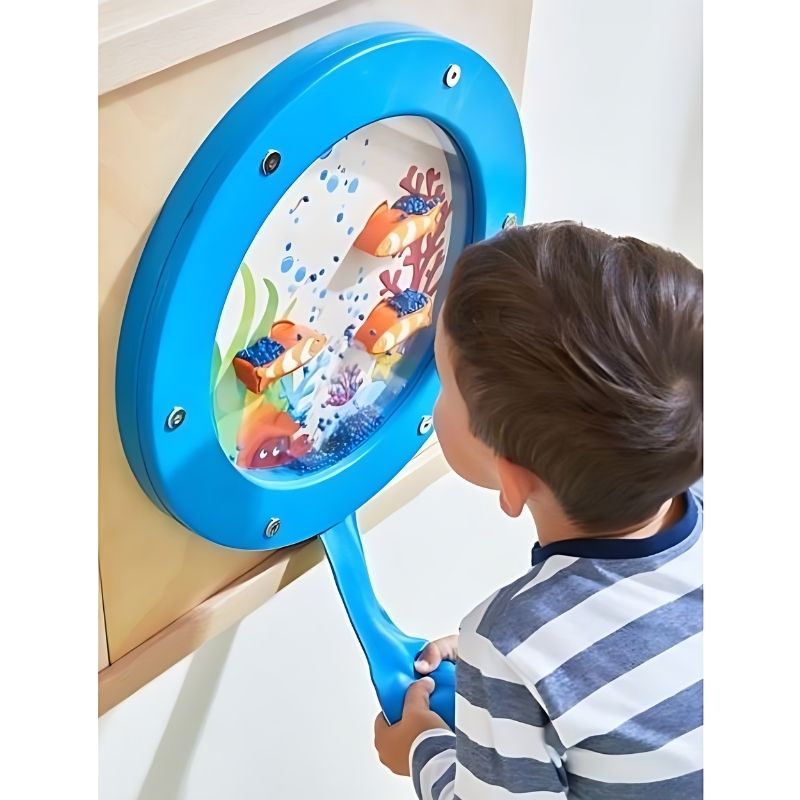 Young boy squeezing the bellows bag on the HABA Pro Ocean Sensory Wall Panel, engaging in tactile sensory wall play and fine motor skill development