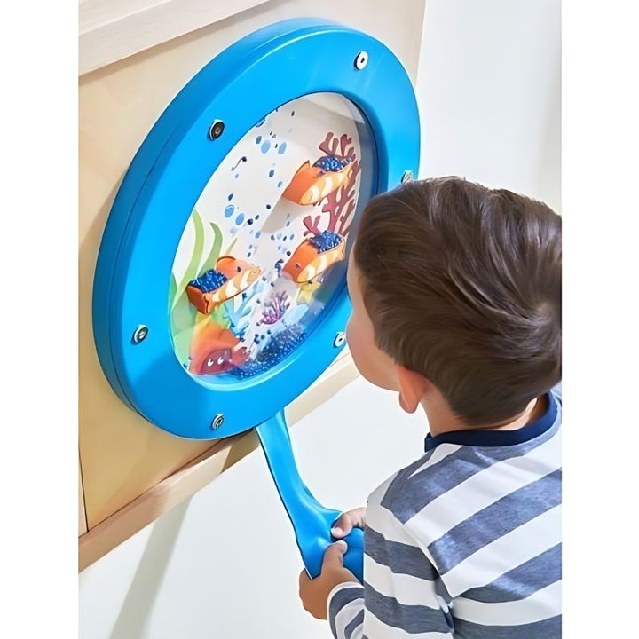 Young boy squeezing the bellows bag on the HABA Pro Ocean Sensory Wall Panel, engaging in tactile sensory wall play and fine motor skill development