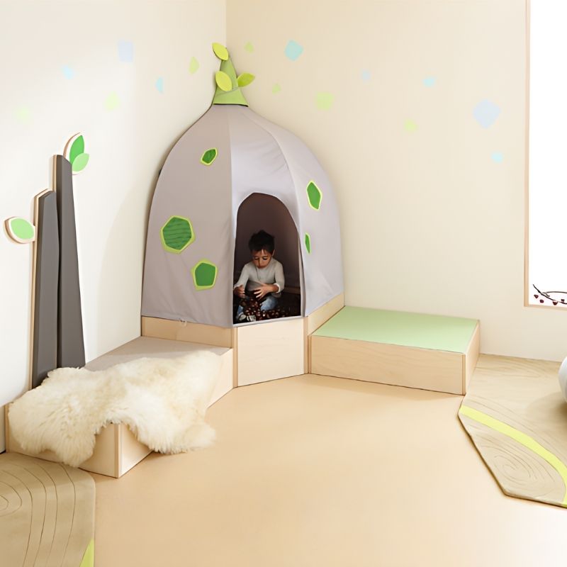 Child seated inside the HABA Pro Grow.upp corner cave on the sensory bath platform, showing the full quiet corner configuration in a nature-inspired classroom