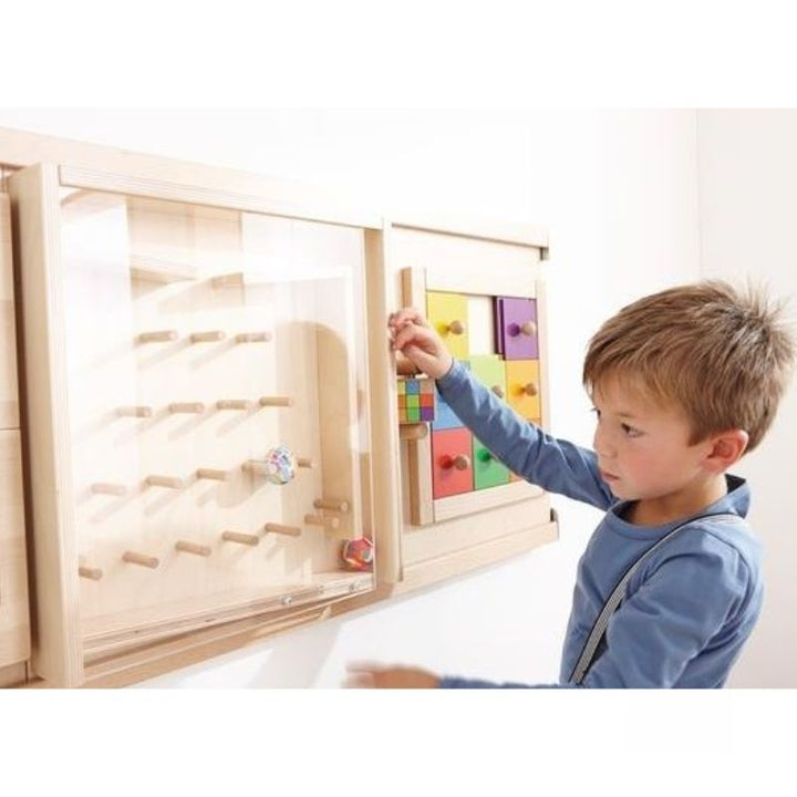 Child using the HABA Pro interactive sensory wall pattern activity in a group room setting, demonstrating tactile and cognitive engagement