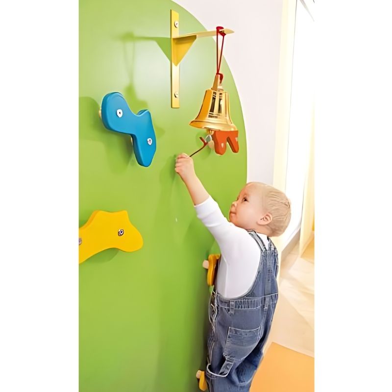 HABA Pro Toddler Climbing Wall close-up of a child reaching the bell at the top of the indoor toddler climbing wall, a motivational goal for young climbers
