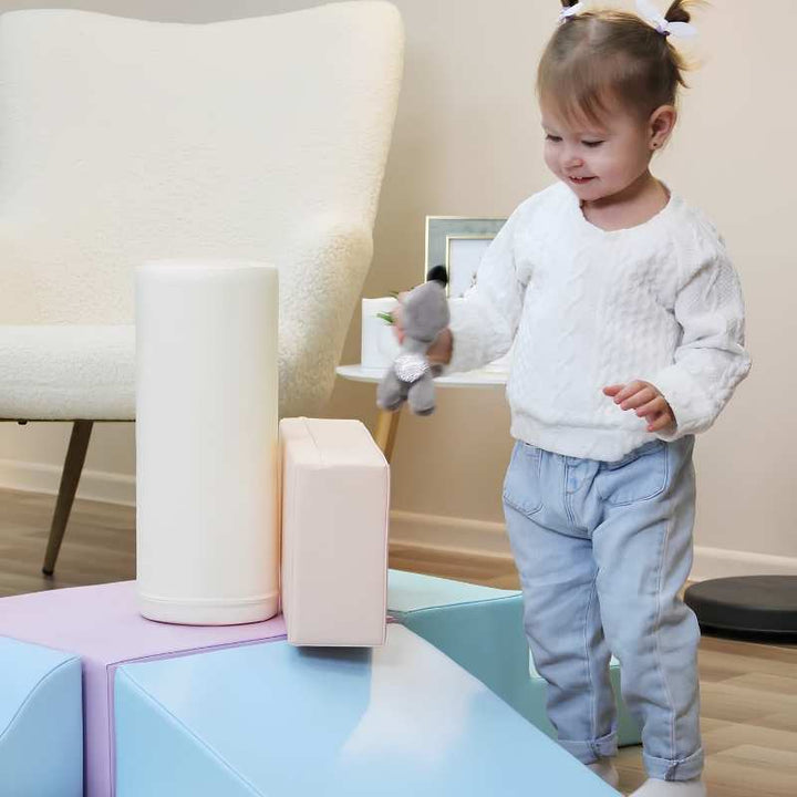 Toddler girl playing with the foam cylinder from the IGLU Explorer Soft Play Set in a pastel colourway