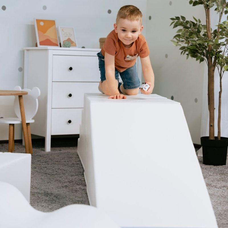 Boy sliding down the IGLU Step and Slide, gross motor foam play equipment from the IGLU Soft Play Party Set