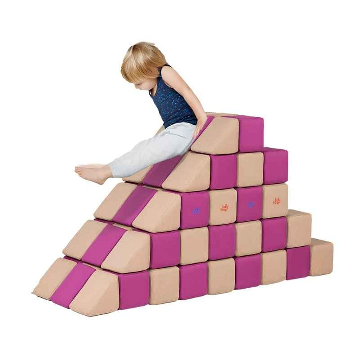 A child climbs a stepped pyramid built from JollyHeap Basic Set magnetic foam blocks, showing the safe climbing and exercise object builds this soft play set supports.
