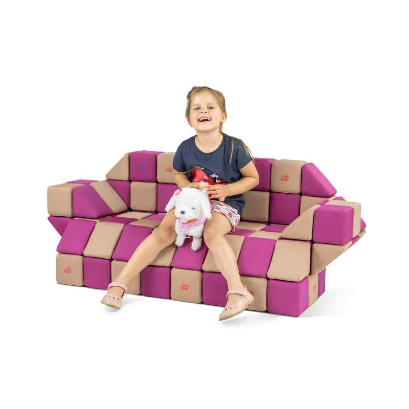 A girl holds a stuffed toy while sitting on a couch built from JollyHeap Basic Set magnetic foam blocks, showing this soft play set's use as functional furniture.