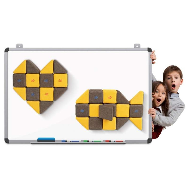 Two children peeking at a heart and fish built from JollyHeap magnetic soft blocks mounted on a classroom whiteboard