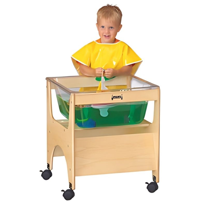 Child actively playing at the Jonti-Craft See Thru Mini Sensory Table 24-1/2" High showing the compact clear acrylic tub and preschool standing height of this GREENGUARD Gold certified sensory table