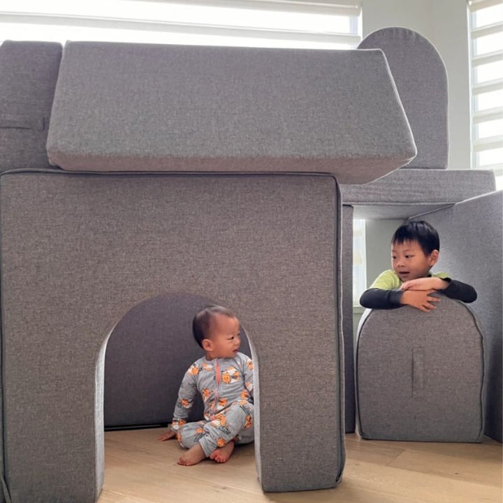 Two children playing actively on the KiiCo Couch MAX modular play couch, showing the gross motor and proprioceptive play the CertiPUR-US certified foam set supports
