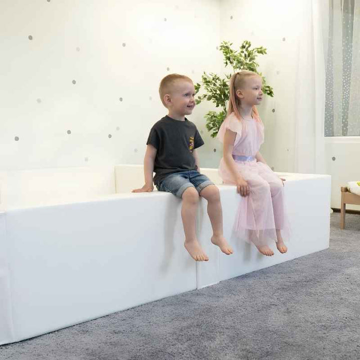 Two children sitting inside the IGLU Large Square Ball Pit, a large foam ball pit for schools and family playrooms