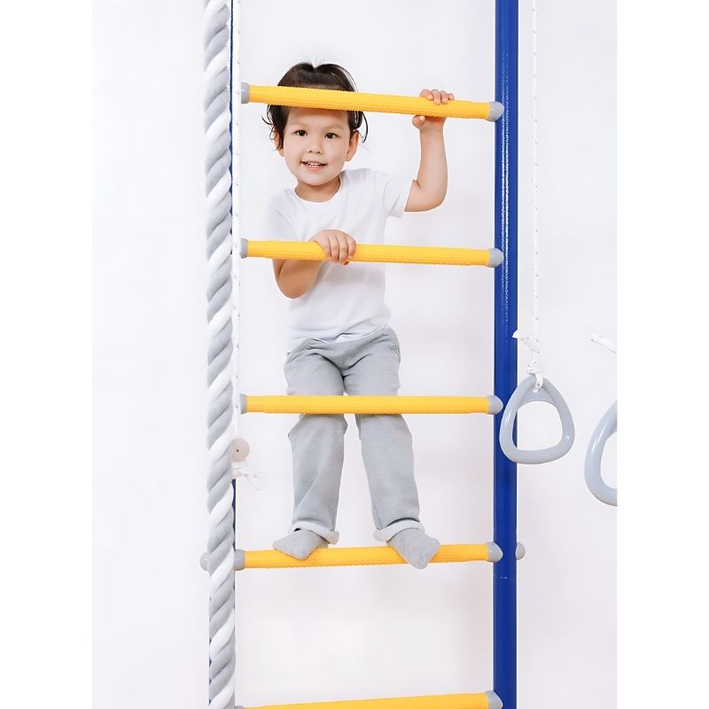 Child actively playing on the LimiKids Comet indoor jungle gym, demonstrating the gross motor, vestibular, and proprioceptive development benefits of the Canadian-made compact indoor playset