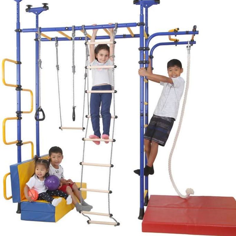 Close-up of children actively playing on the LimiKids Pegasus indoor playset, showing hands-on use of the monkey bars and gymnastic rings for gross motor, brachiation, and vestibular development