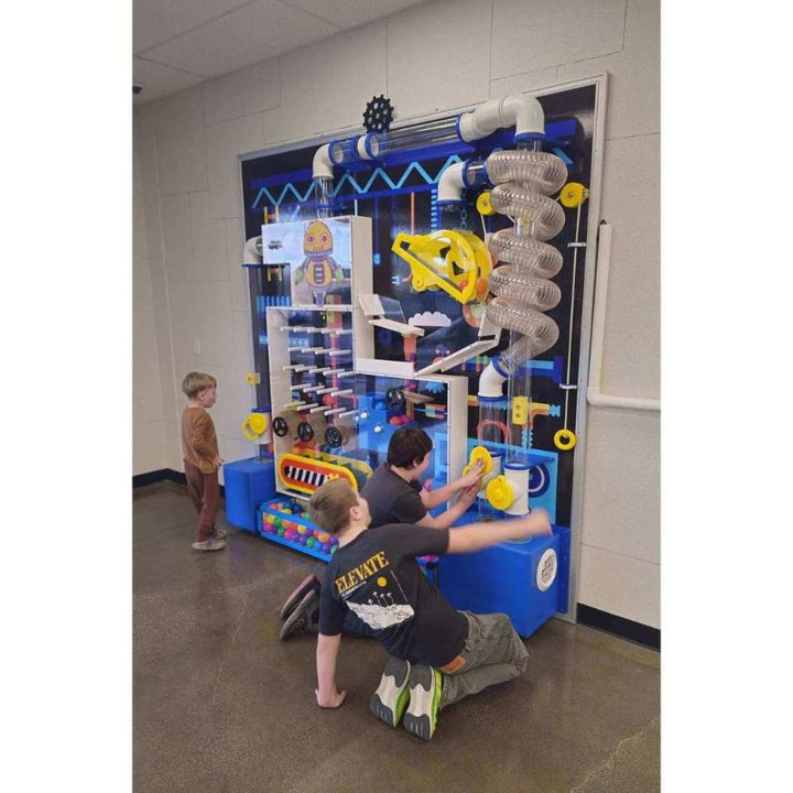 LiteZilla Ultimate Ball Launcher 8x8 configuration installed in a school or recreation centre, with children engaging at the exhibit base and plinko tracks, demonstrating the unit's scale for institutional STEM and sensory play settings