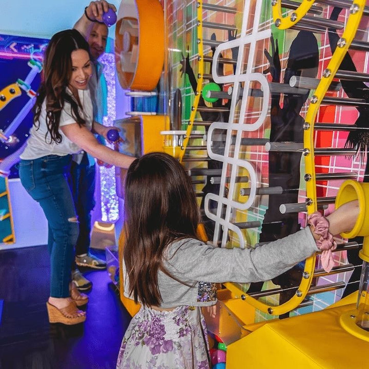 An adult and child playing together with the LiteZilla Ultimate Ball Launcher in a sensory room environment, demonstrating how the air-powered exhibit engages all ages through shared interactive STEM play