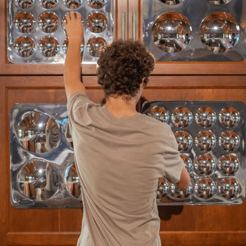 Child standing before the LiteZilla Sensory Bubble Mirror Panel exploring distorted reflections, supporting visual tracking and cognitive development