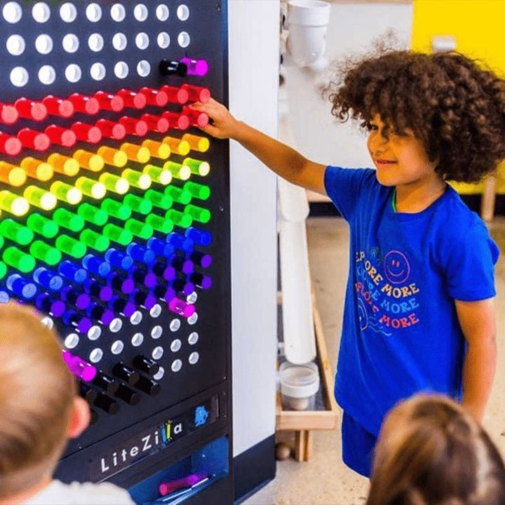 Boy actively playing at the LiteZilla Giant Lite Brite sensory light wall, creating a colourful glowing pattern with LitePins