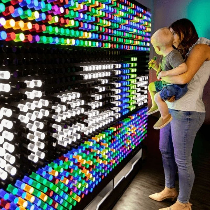 LiteZilla Giant Lite Brite interactive sensory light wall with a mother and two children inserting colourful LitePins into the backlit grid