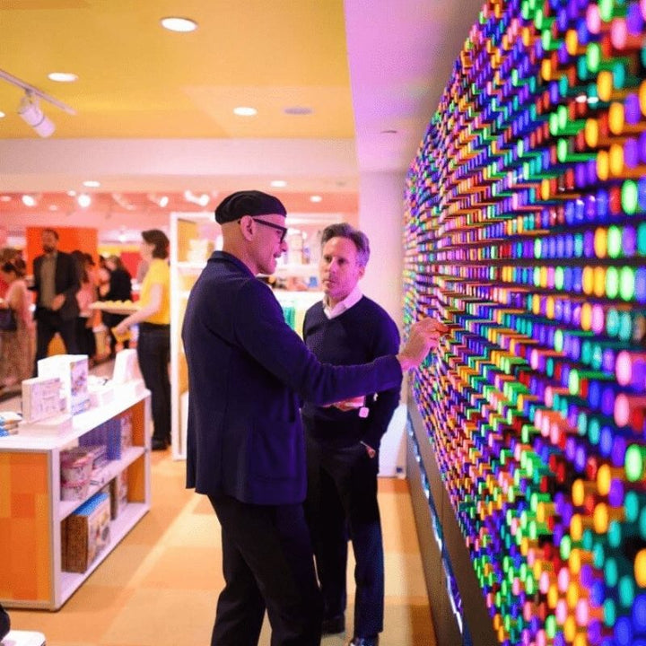 Two adults engaged in collaborative play on the LiteZilla Giant Lite Brite interactive sensory light wall