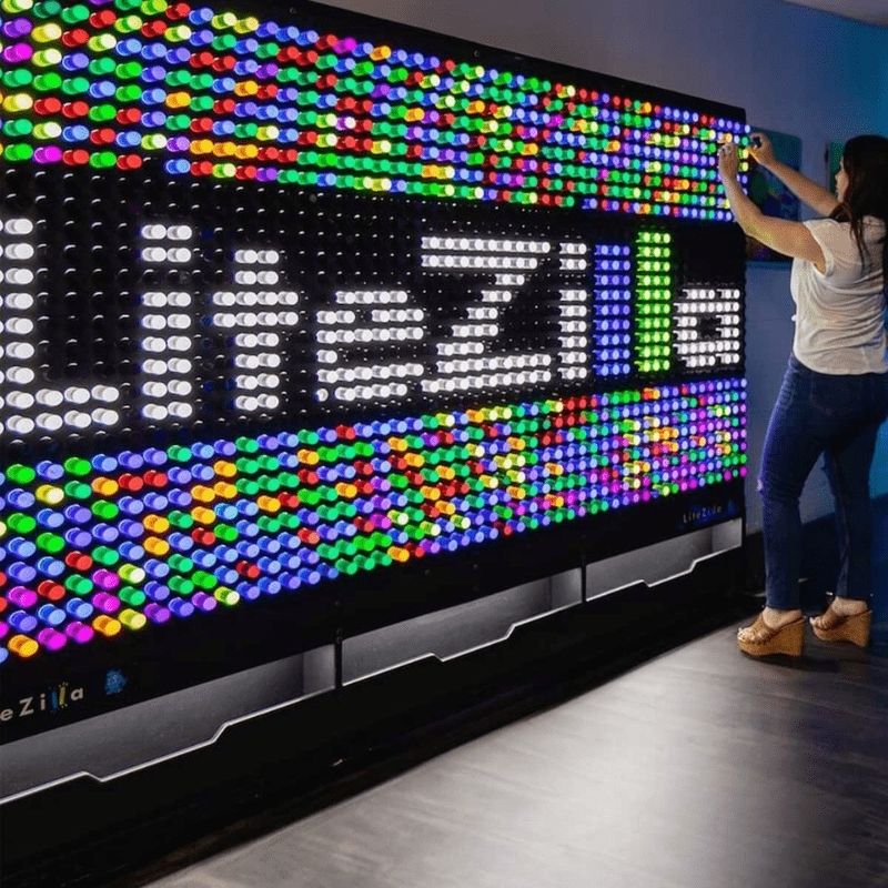 Woman inserting LitePins into the LiteZilla Giant Lite Brite sensory light wall, demonstrating fine motor engagement and visual stimulation