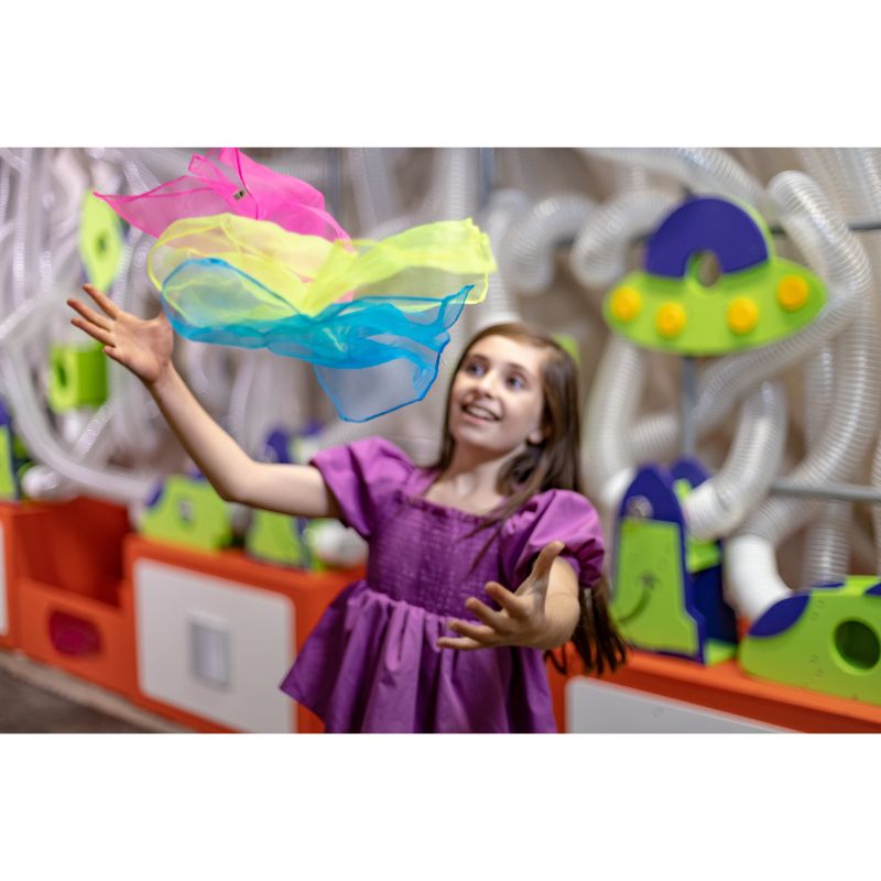 Child catching a scarf launched from the LiteZilla Ultimate Scarf Launcher air tube exhibit during active sensory play