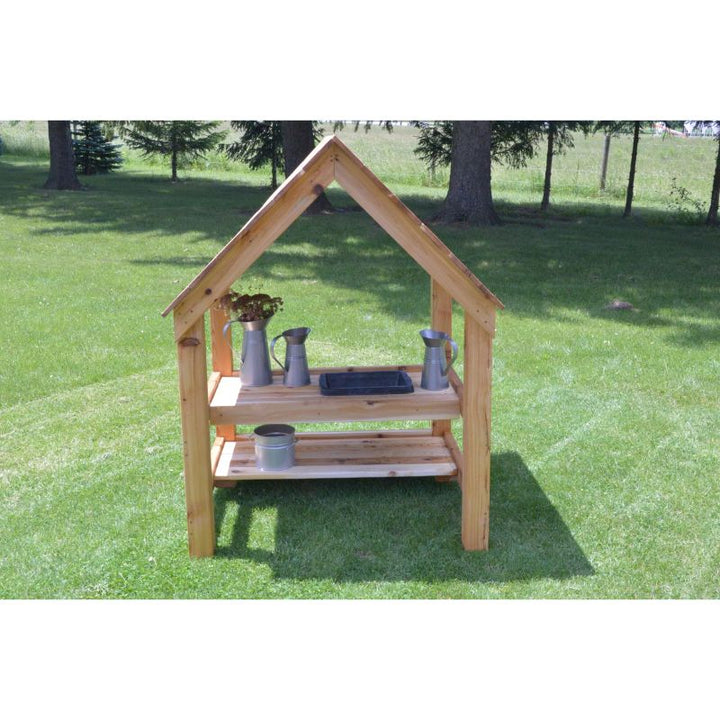 ONP Mud Kitchen House in portrait view styled with play accessories, showing the sheltered cedar outdoor kitchen structure set up for early years messy play and role play