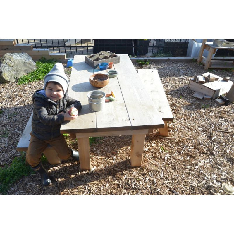 ONP Pre-School Project Table and Benches in North American Cedar showing a child seated at the table, designed for outdoor classroom and preschool group play