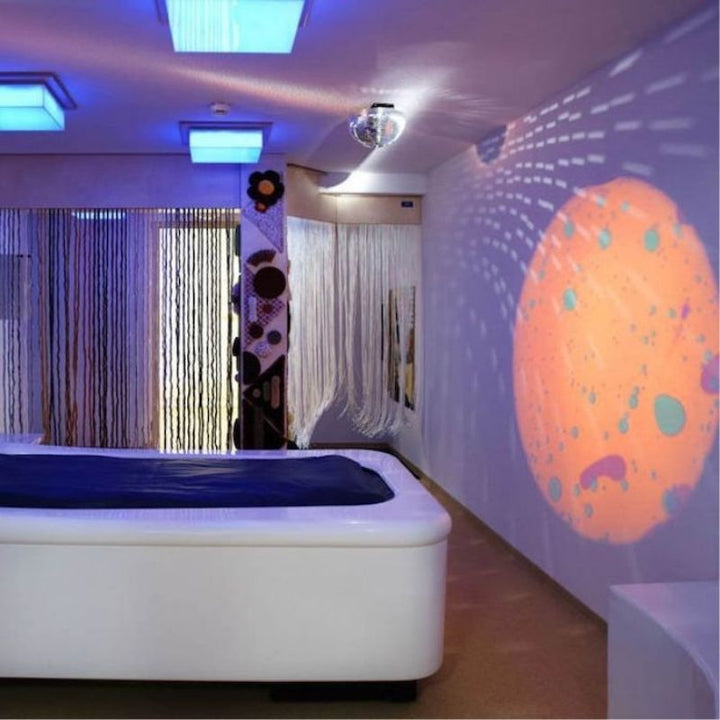 OPTIKinetics Solar 100 LED projector in a bedroom sensory environment, showing how the effects projector transforms a home space into a calming sensory oasis