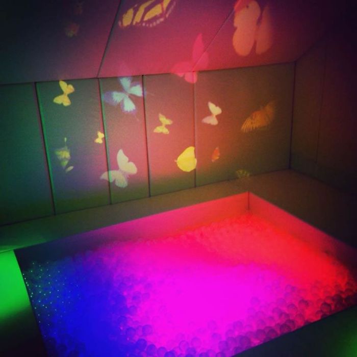 OPTIKinetics Solar 250 LED projector casting butterfly effect wheel projections across a sensory room wall, creating a calming visual environment for therapy and learning