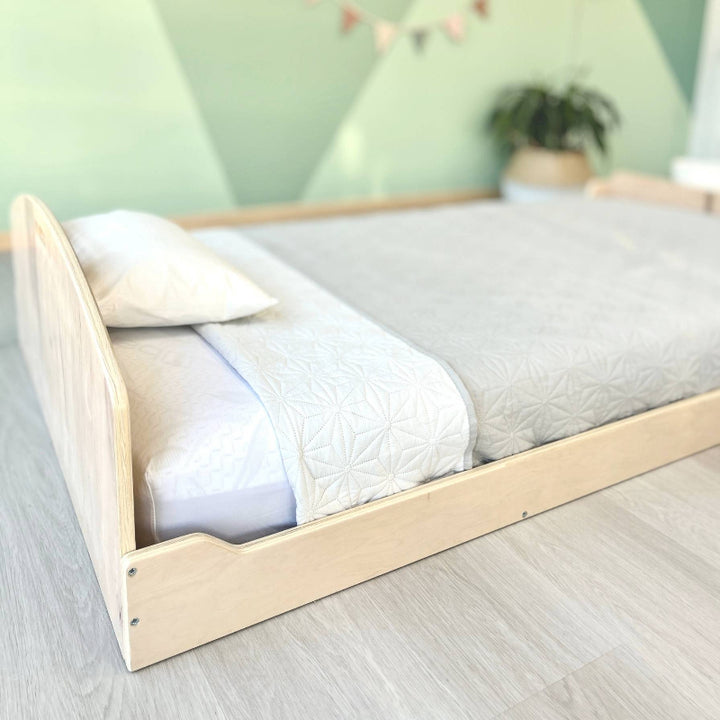 Landscape view from the headboard of the Sapiens Child Cherry Montessori floor bed, showing the slatted base, low profile, and FSC-certified plywood construction